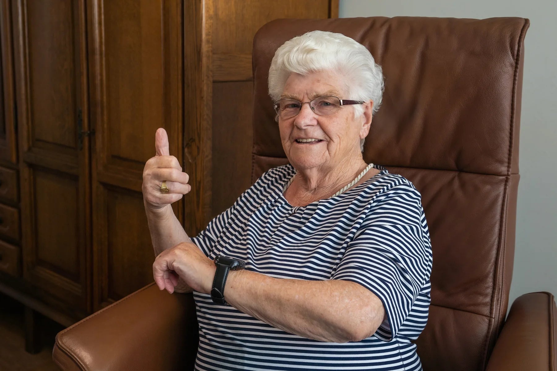Vrouw met het KUUS horloge om haar pols in haar stoel